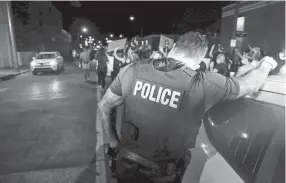  ?? HENRY TAYLOR/USA TODAY NETWORK - TENNESSEE ?? A Memphis Police officer leans against a squad car while a line of protesters passes a corner in downtown in Memphis on May 29.