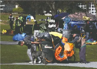  ?? NICK PROCAYLO ?? Residents move their belongings as Vancouver park rangers clear tents outside the designated camping area in CRAB Park on Tuesday. The cleanup of the sanctioned area of the park has been completed.