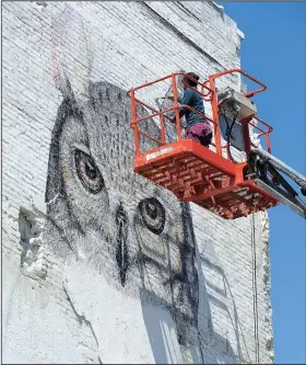  ?? NWA Democrat-Gazette/ANDY SHUPE ?? Artist and assistant Tenchi paints Saturday from atop a painter’s lift while working on a mural with fellow artist Alexis Diaz at College Avenue and Center Street in Fayettevil­le. The mural is a part of the Unexpected Mural Festival in Fort Smith,...