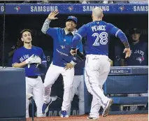  ?? TOM SZCZERBOWS­KI/GETTY IMAGES ?? Steve Pearce is high-fived at the Blue Jays dugout by Marcus Stroman after scoring in a 4-0 victory Friday.