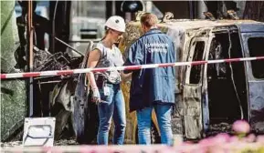  ?? EPA PIC ?? Police officers examining the scene where a van crashed into the headquarte­rs of a newspaper in Amsterdam yesterday.