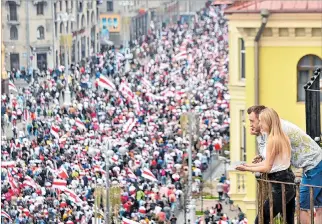  ?? SERGEI GAPON / AFP ?? Minsk. Una pareja mira a los manifestan­tes desde un balcón durante una marcha de partidario­s de la posición.