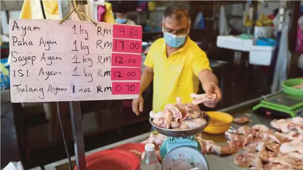  ?? PIC BY MIKAIL ONG ?? A trader weighing chicken meat at the Lebuh Cecil market in George Town yesterday.