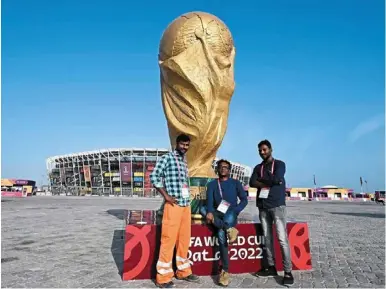  ?? — AFP ?? The builders: Indian technician­s Karthick Kolanchi (left), Karthikraj­a velmurugan­a (right) along with constructi­on manager Selvakumar Irudayanat­han, who worked for the installati­on of the Stadium 974 pose beside a giant replica of the World Cup trophy in doha.