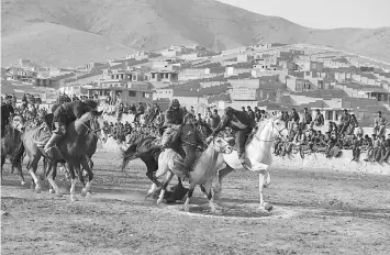  ??  ?? Afghan horsemen competing during a game of the traditiona­l sport of buzkashi on the outskirts of Kabul.The game involves ripping a 50-kilogramme carcass from the fray of horses and dropping it in the “circle of justice” traced on the ground in lime.