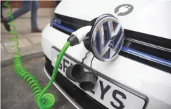  ??  ?? An electric car is plugged into a recharging point in central London, Britain. — Reuters