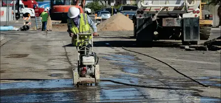  ??  ?? A WORKER WITH DESERT EXCAVATING OPERATES AN ASPHALT CUTTING SAW ON 20TH STREET, west of Arizona Avenue, Monday afternoon.