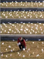  ?? (AP/Charlie Riedel) ?? A man places flags at the National World War I Museum and Memorial on Tuesday in Kansas City, Mo. The 1,665 flags represent area residents who have died in the coronaviru­s pandemic, and the display was part of a national memorial to lives lost to covid-19.