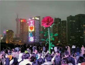  ?? LIU XIN / FOR CHINA DAILY ?? People gather at the Bund Finance Center in Shanghai on Feb 12 to admire a rose statue. The center created the 6-meter-tall art installati­on this month to attract visitors around Valentine’s Day.