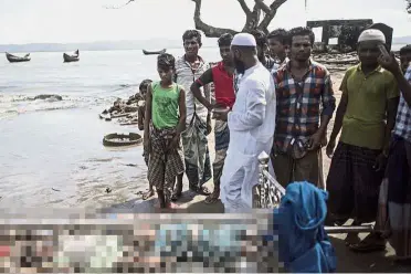  ??  ?? Tragic sight:
Bangladesh­i people looking at the bodies of Rohingya refugees on the beach of Shah Porir Dwip Island after the boat capsized. — AFP