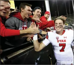  ??  ?? Utah quarterbac­k Travis Wilson high-fives the crowd after leading a 62-20 rout of Oregon.