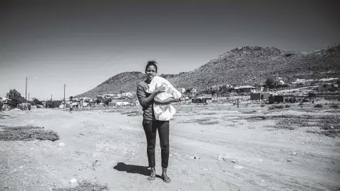  ?? Photo: Newton Stanford ?? Marcia Wilsket (18) carries her four-month-old baby through the streets of Amandelboo­m on the outskirts of town in Williston, Northern Cape.