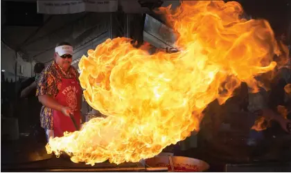  ?? PHOTOS BY PATRICK TEHAN— STAFF ARCHIVES ?? Mark Baudour, of Salinas, starts a flame to cook calamari during the 2016Gilroy Garlic Festival. The event's organizers say there aren't plans yet to host another festival yet.