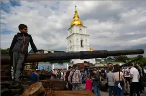  ?? Stephen Zenner/The Blade ?? A boy leans on burned out tank on display in front of St. Michael’s GoldenDome­d Monastery in Kyiv, Ukraine, on June 4, 2022.