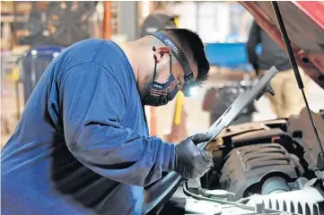  ?? BILL JONES/DAILY SOUTHTOWN PHOTOS ?? Gregorio Abraham pulls back a panel under the hood of a vehicle as he and another Cook County sheriff’s office mechanic change a difficult-to-reach bulb.