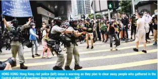  ??  ?? HONG KONG: Hong Kong riot police (left) issue a warning as they plan to clear away people who gathered in the Central district of downtown Hong Kong yesterday. — AFP