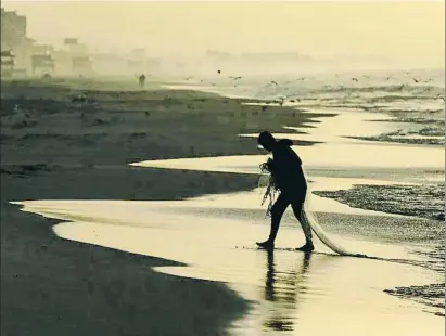  ?? MAHMUD HAMS / AFP ?? Ferides obertes. Un pescador palestí camina amb una xarxa a la platja de Gaza; la tensió entre palestins i israelians s’ha agreujat amb la decisió de Trump sobre Israel