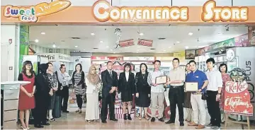  ??  ?? Khiew (front, third right) hands over the ‘KitKat Merchandis­ing Award’ to Sing Siew in front of the SFCS at KIA.