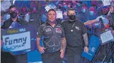  ?? FOTO: SIMON WEST/IMAGO IMAGES ?? Volles Haus, kaum Masken: Corona wirbelt die Darts-WM gehörig durcheinan­der. Gerwyn Price (Mi.) hat deshalb eine Verschiebu­ng ins Spiel gebracht.