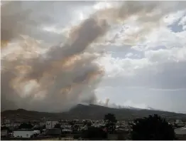  ?? (Alkis Konstantin­idis/Reuters) ?? A VILLAGE IS SEEN amid smoke as a wildfire burns in Kineta, near Athens, Greece, yesterday.