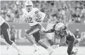  ?? JULIO AGUILAR/GETTY ?? Tulane’s Justin McMillan, left, breaks a USF tackle during the Green Wave’s rout of the Bulls Saturday in Tampa.