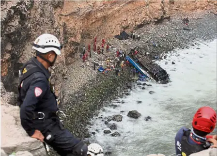  ?? — Reuters ?? Death route: Rescue workers at the scene and an injured passenger (right) being winched to safety along a sharp curve in the road north of Lima.