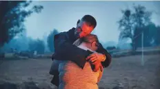  ?? AP ?? Phillip Harvey embraces his daughter Arianne Harvey as they stay warm beside a fire in Paradise. Phillip and Krystin, who lost their mobile home, had been staying with Arianne and their two other teenage daughters in the camper.