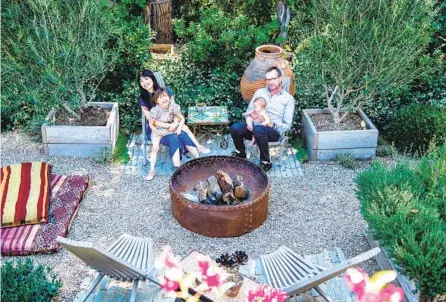  ?? MARIAH TAUGER LOS ANGELES TIMES ?? The Robbins family of four relax in their gravel-covered backyard fire pit area, a favorite hangout accompanie­d by a raised-bed herb garden and a collection of potted plants that complement the mass plantings that surround the space.