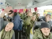  ?? RUSSIAN DEFENSE MINISTRY PRESS SERVICE ?? Russian soldiers wave after they were released Saturday in a prisoner swap with Ukraine. Russia said that 63 of its soldiers were returned.