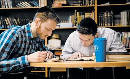  ?? LUIS ANDRES HENAO/AP ?? Yeshiva University students Aaron Heideman, left, and Marc Shapiro study at the university’s library Thursday in New York. Heideman said the president’s order will help his friends at secular universiti­es who have run into problems.