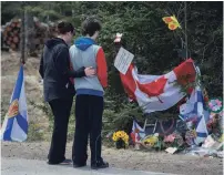  ?? ANDREW VAUGHAN THE CANADIAN PRESS ?? Visitors pay their respects at a roadside memorial in Portapique, N.S., on Friday. The murder spree last week claimed 22 victims.
