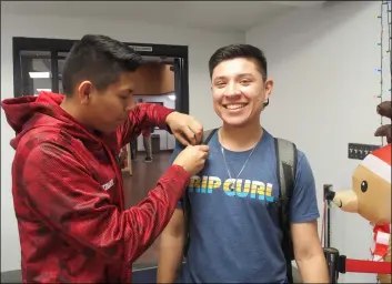  ??  ?? Associated Student Gov. Moises Hernandez pinning Imperial Valley College student Victor Felix with a red ribbon for their HIV awareness event hosted on World AIDS Day. PHOTO ANDY VELEZ