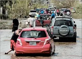  ?? CARLOS GIUSTI/ASSOCIATED PRESS ?? Residents in Toa Baja drive Friday on a road flooded by Hurricane Maria. Concerns over a dam failure led to the evacuation of 70,000 people in Isabela and Quebradill­as.