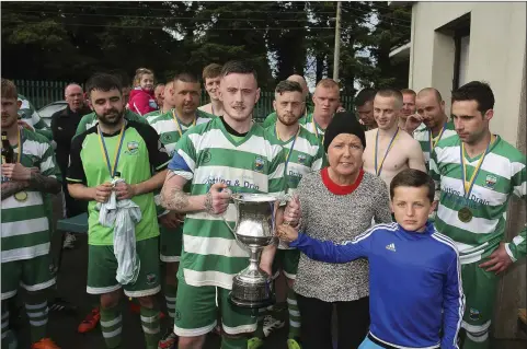  ??  ?? Arklow Celtic captain Shane Walker receives the Thomas Scott Cup from Elizabeth Kinsella and Gavin Cullen.