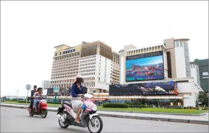  ?? HENG CHIVOAN ?? Traffic passes in front of Phnom Penh’s landmark NagaWorld hotel and casino complex.