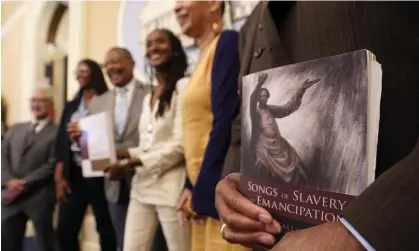  ?? Photograph: Rich Pedroncell­i/AP ?? Amos Brown, the vice-chair for the California taskforce, right holds a copy of the book Songs of Slavery and Emancipati­on, at an event in Sacramento in June.