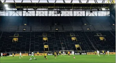  ?? AP PHOTO BY MARTIN MEISSNER ?? In this Feb. 18, 2017 file photo, players challenge for the ball in front of the empty south tribune because of a ban following fan trouble during the German Bundesliga soccer match between Borussia Dortmund and VFL Wolfsburg at Germany’s biggest stadium in Dortmund, Germany. Bundesliga will now restart on May 16, 2020 when Dortmund will play the derby against Schalke at home without spectators due to the coronaviru­s outbreak.