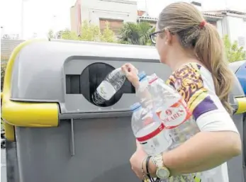  ??  ?? Una mujer deposita varias botellas de plástico en un contenedor de la calle Muro.