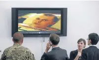  ?? Photos: REUTERS ?? Ukrainian journalist­s and a serviceman look at a video of Russian soldiers allegedly captured by Ukrainian troops before a news conference in Kiev.