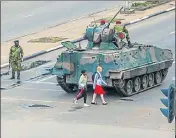  ?? AFP ?? Young women walk past an armoured vehicle stationed by an intersecti­on as Zimbabwe soldiers regulate traffic in Harare.