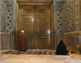  ?? THE ASSOCIATED PRESS ?? A cleric and a woman pray behind a closed door of Masoume shrine in the city of Qom, Iran, some 80miles south of the capital Tehran, on Monday.