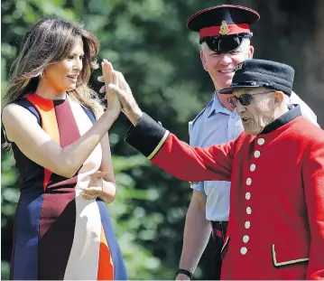  ?? LUCA BRUNO / WPA POOL / GETTY IMAGES ?? U.S. first lady Melania Trump high-fives a British “Chelsea Pensioner” veteran during a game of lawn bowling at Royal Hospital Chelsea in London on Friday while her husband, President Donald Trump, held bi-lateral talks with Prime Minister Theresa May.