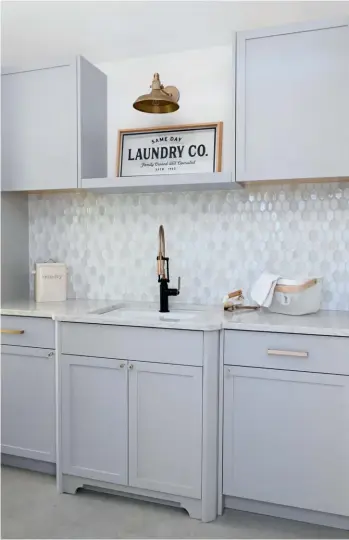  ??  ?? ABOVE The home’s former garage is now a swish laundry room with extra storage for staples such as batteries, light bulbs and detergent. “For someone as organized as this homeowner, a space like this is a dream come true,” says Sarah. The honeycomb shape of the backsplash tile is inspired by the shapes in the home’s leaded glass windows.
TILE, Terra Sol Tile. WALL LAMP, RH.