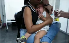  ??  ?? A Venezuelan woman holds her son as he receives a free vaccinatio­n after showing their identifica­tion documents at the Pacaraima border control, Roraima state. — Reuters photo