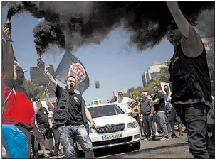  ?? AP ?? Demonstrat­ors with Spanish taxi-driver unions wave flares as they protest this summer in Madrid against companies such as Uber and Cabify, which they accused of unfair competitio­n.