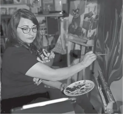 ?? GABY VELASQUEZ/ EL PASO TIMES ?? El Paso artist Blanca Estrada glances over at her reference photo as she works on a commission­ed painting in her home studio in El Paso on March 22.