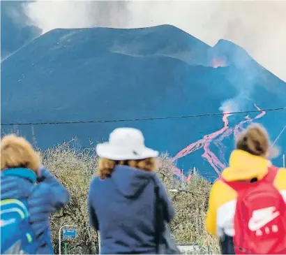  ?? ANGEL MEDINA G. / EFE ?? Tres dones observen el descens de diverses colades de lava del Cumbre Vieja