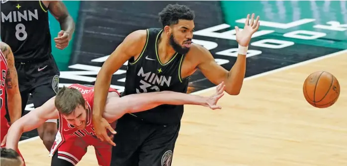  ?? NAM Y. HUH/AP ?? Bulls center Luke Kornet and Timberwolv­es center Karl-Anthony Towns battle for a loose ball during the first half Wednesday at the United Center.