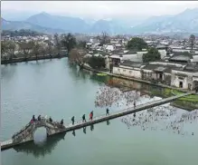  ?? SHI YALEI / XINHUA ?? Tourists cross a bridge in Hongcun Ancient Village, Yixian county, Anhui province.