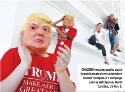  ??  ?? CHILDREN wearing masks watch Republican presidenti­al nominee Donald Trump hold a campaign rally in Wilmington, North Carolina, US Nov. 5.